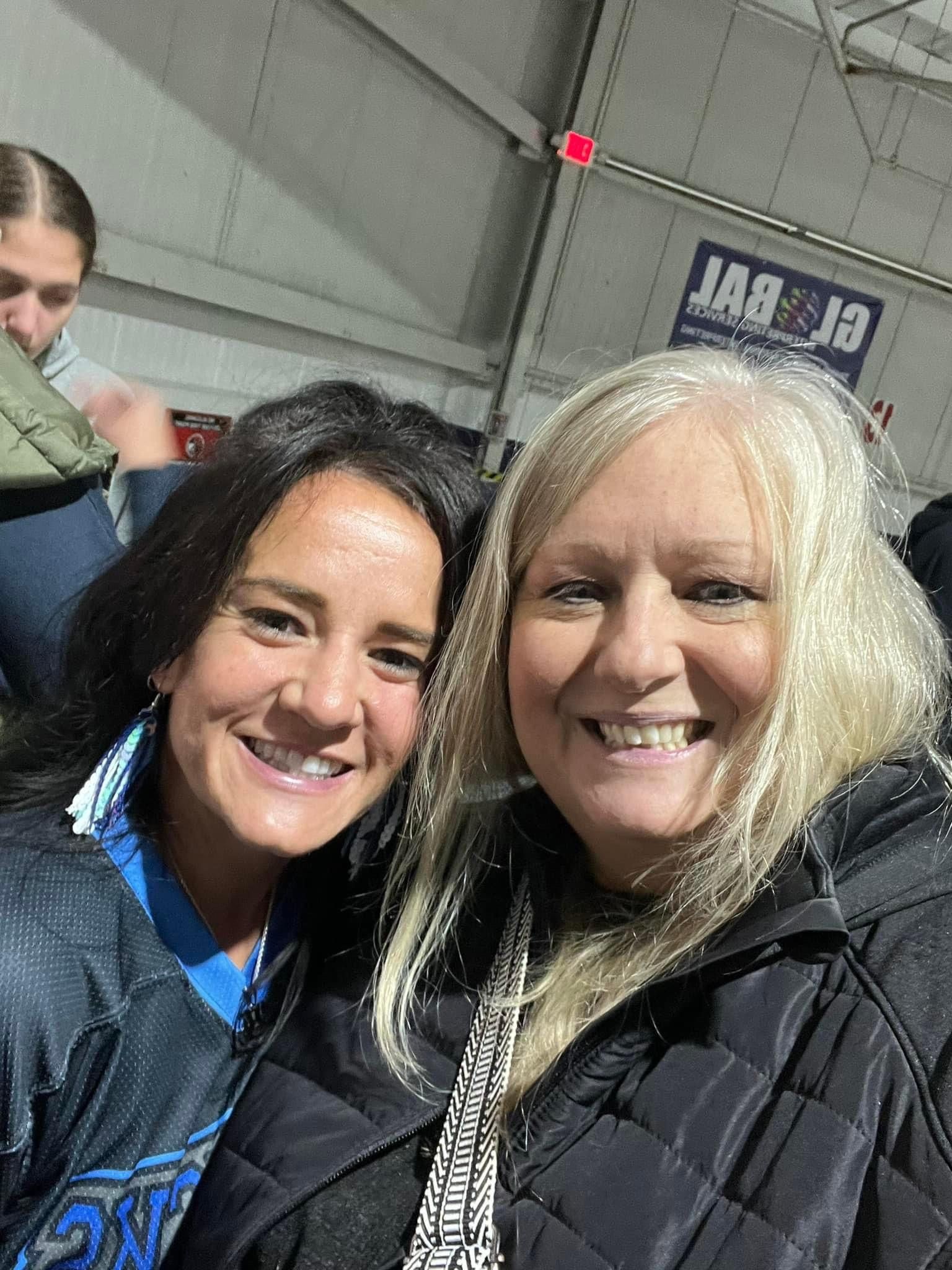 Two women are posing for a picture together and smiling for the camera.