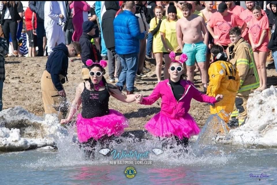 Two women in pink tutus are holding hands in the water