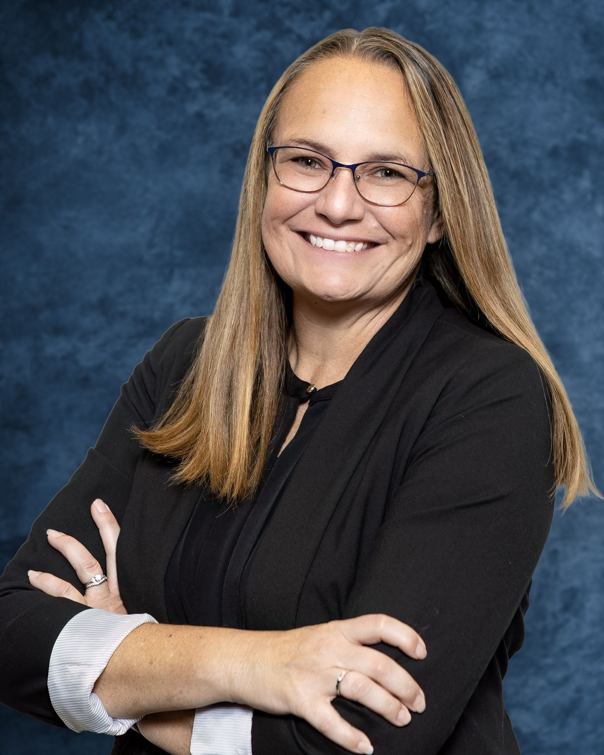 A woman wearing glasses and a black shirt smiles for the camera