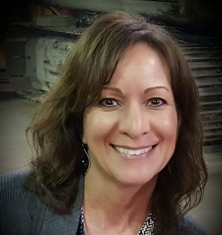 A woman with long brown hair is smiling for the camera.