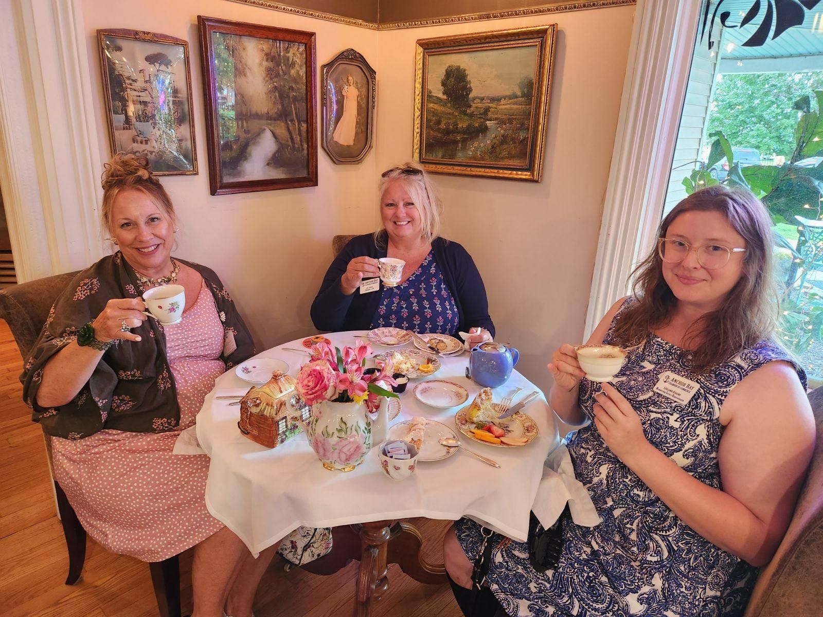 Three women are sitting at a table drinking tea