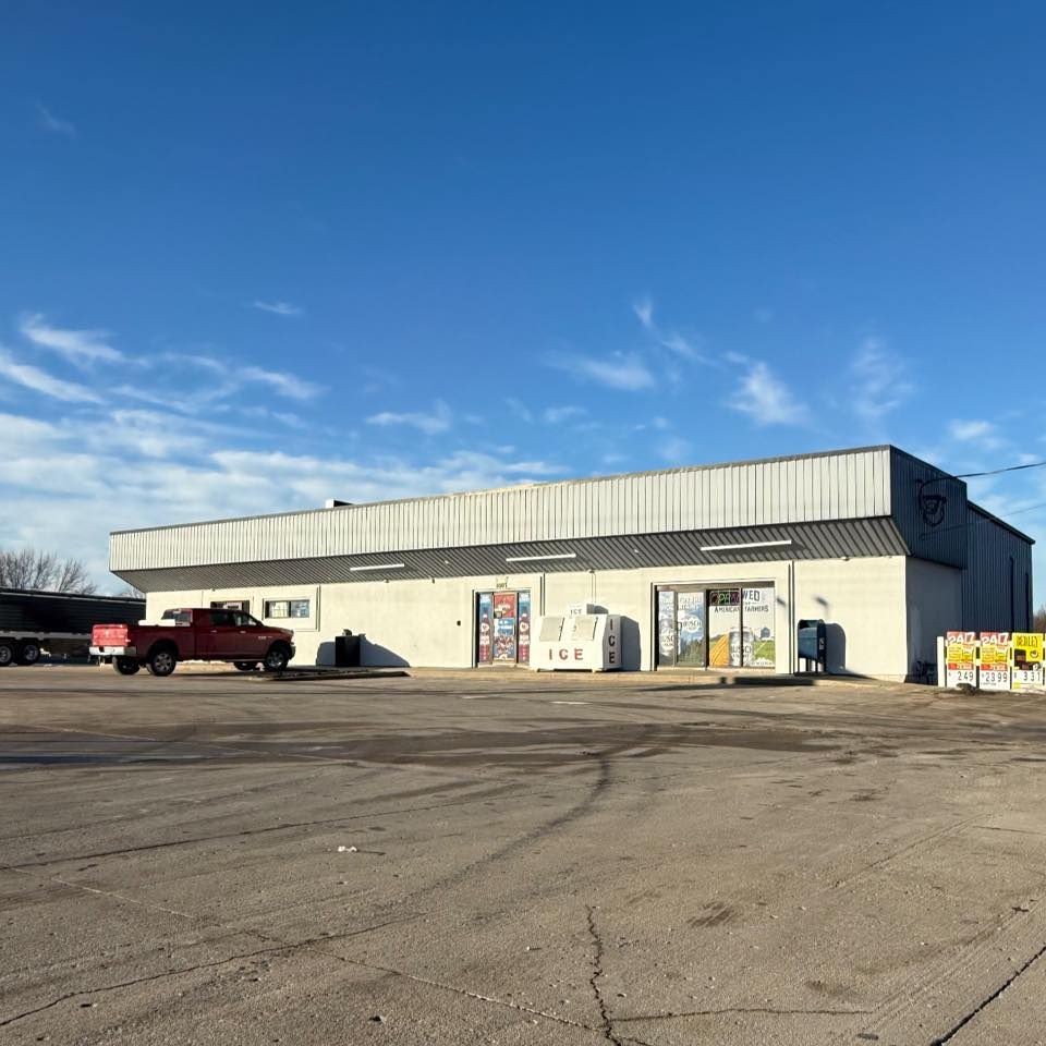 A red truck is parked in front of a white building.