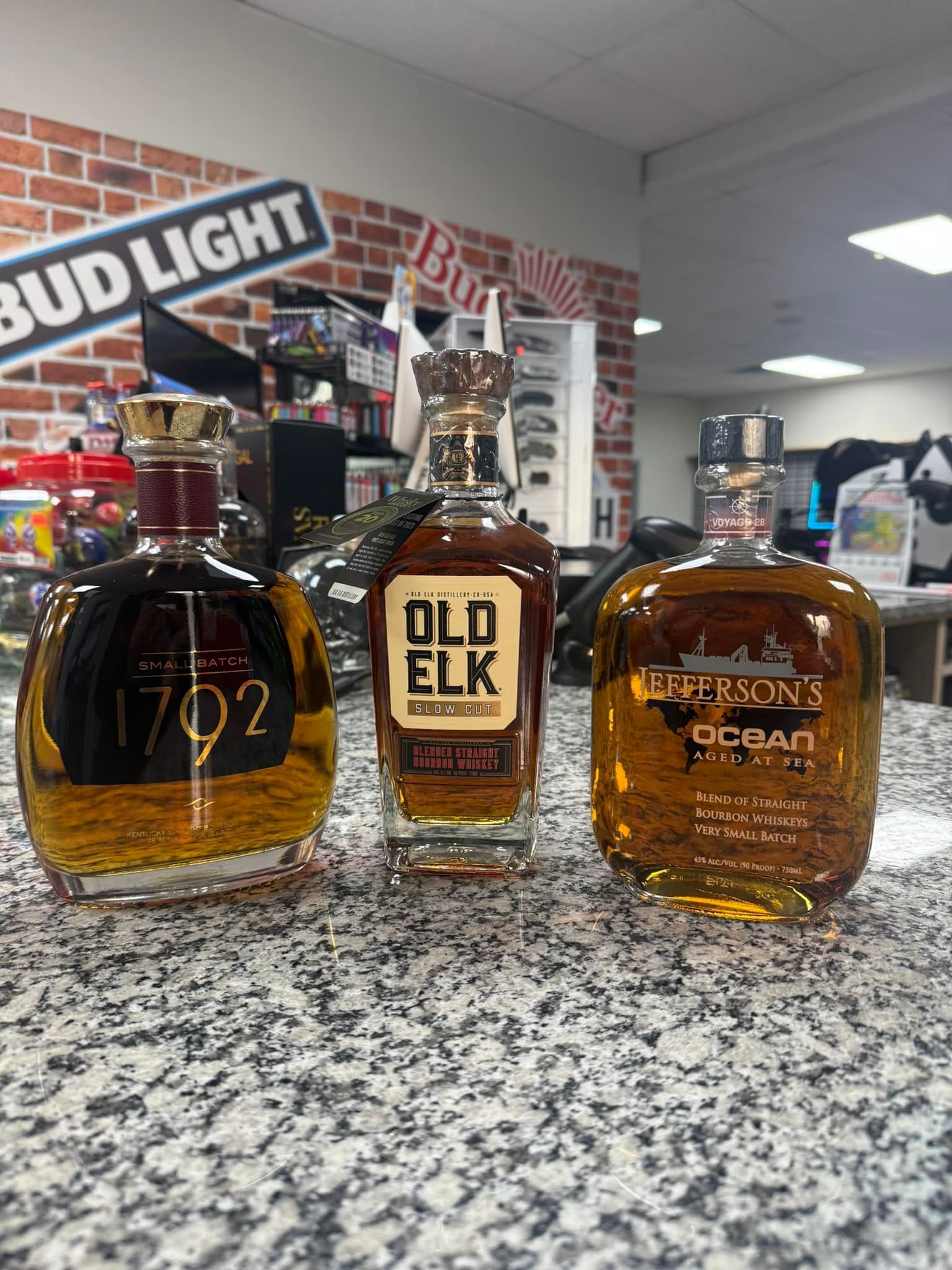 Three bottles of alcohol are sitting on a counter.