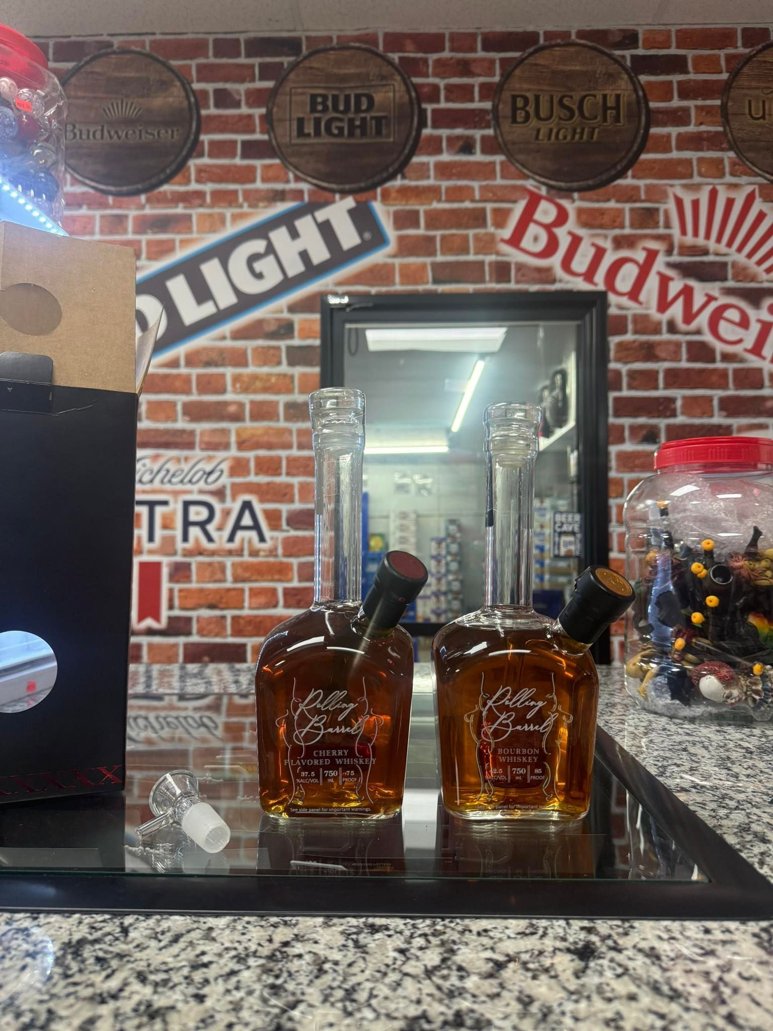 Two bottles of whiskey are sitting on a counter in front of a brick wall.