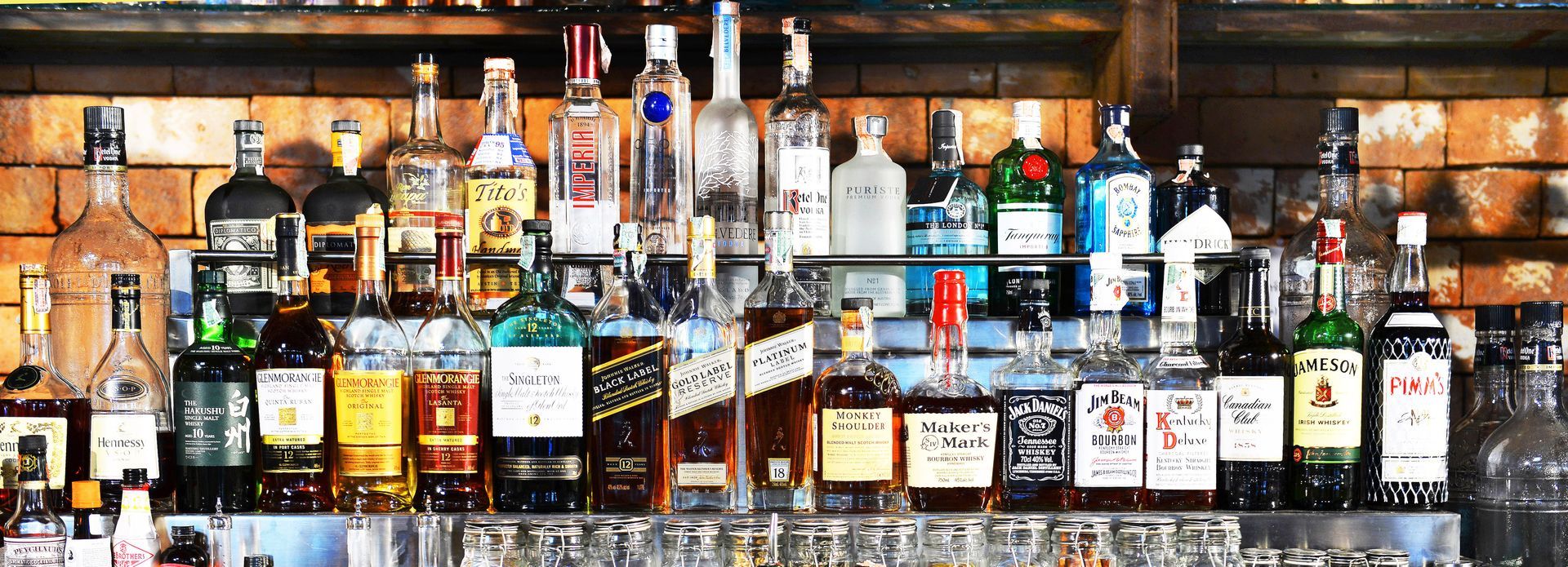 A bar filled with lots of bottles of liquor and glasses.