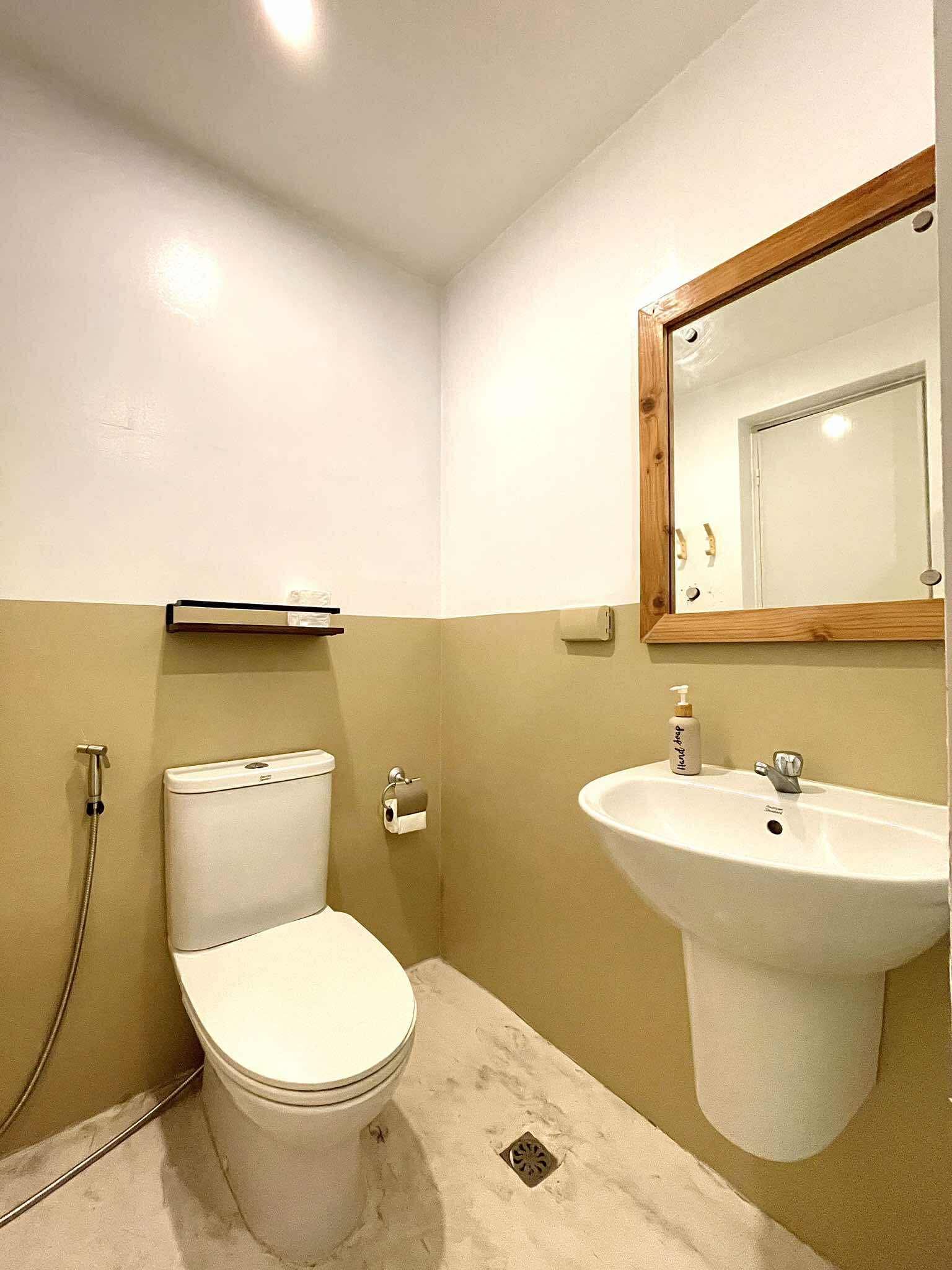 Small bathroom with a toilet, sink, and mirror. White and beige walls.