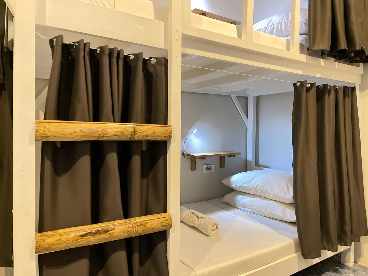 Bunk beds in a white-walled room with gray curtains and wooden accents.