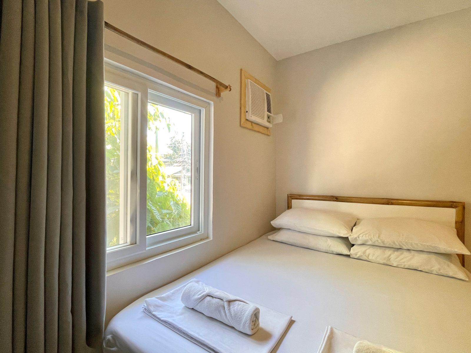 Bedroom with a bed, window with light, and closed curtains.