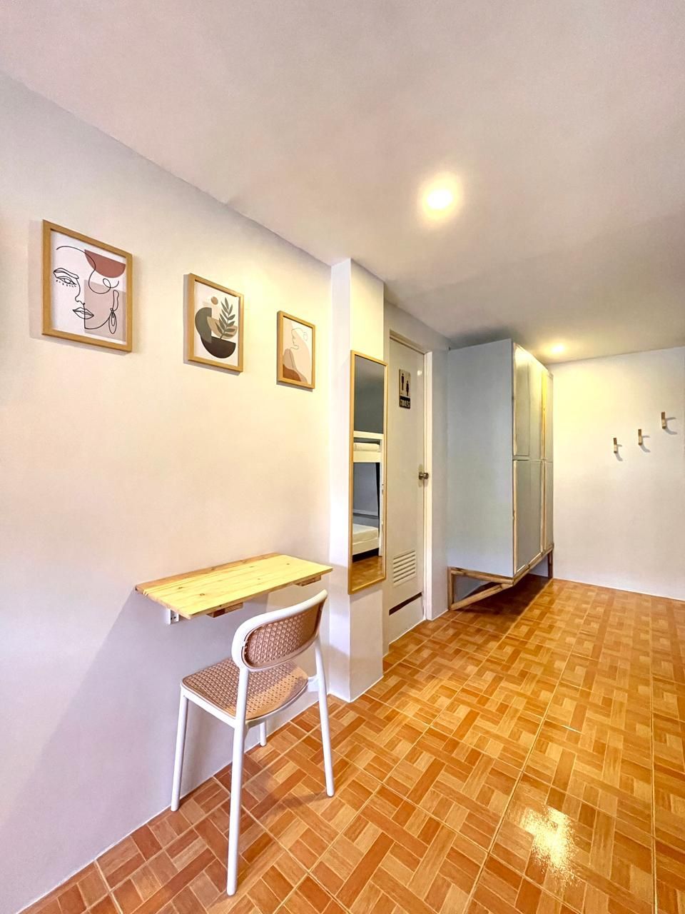 Small room with a desk and chair, art on the wall, and a tiled floor.
