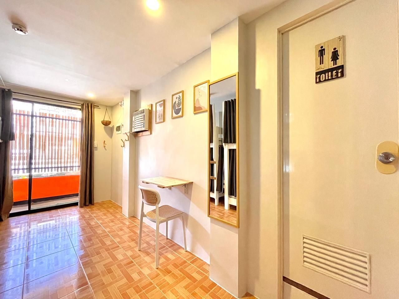 Interior hallway with tiled floor, small desk, mirror, bathroom door, and balcony.
