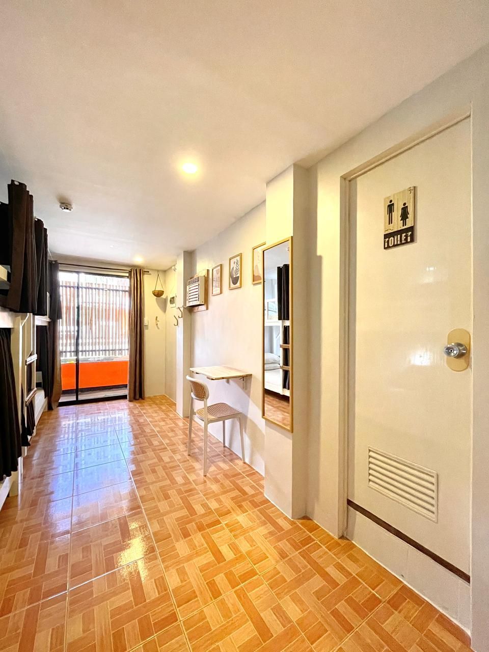 Hallway with tiled floor, bunk beds on the left, and a door with bathroom sign on the right.