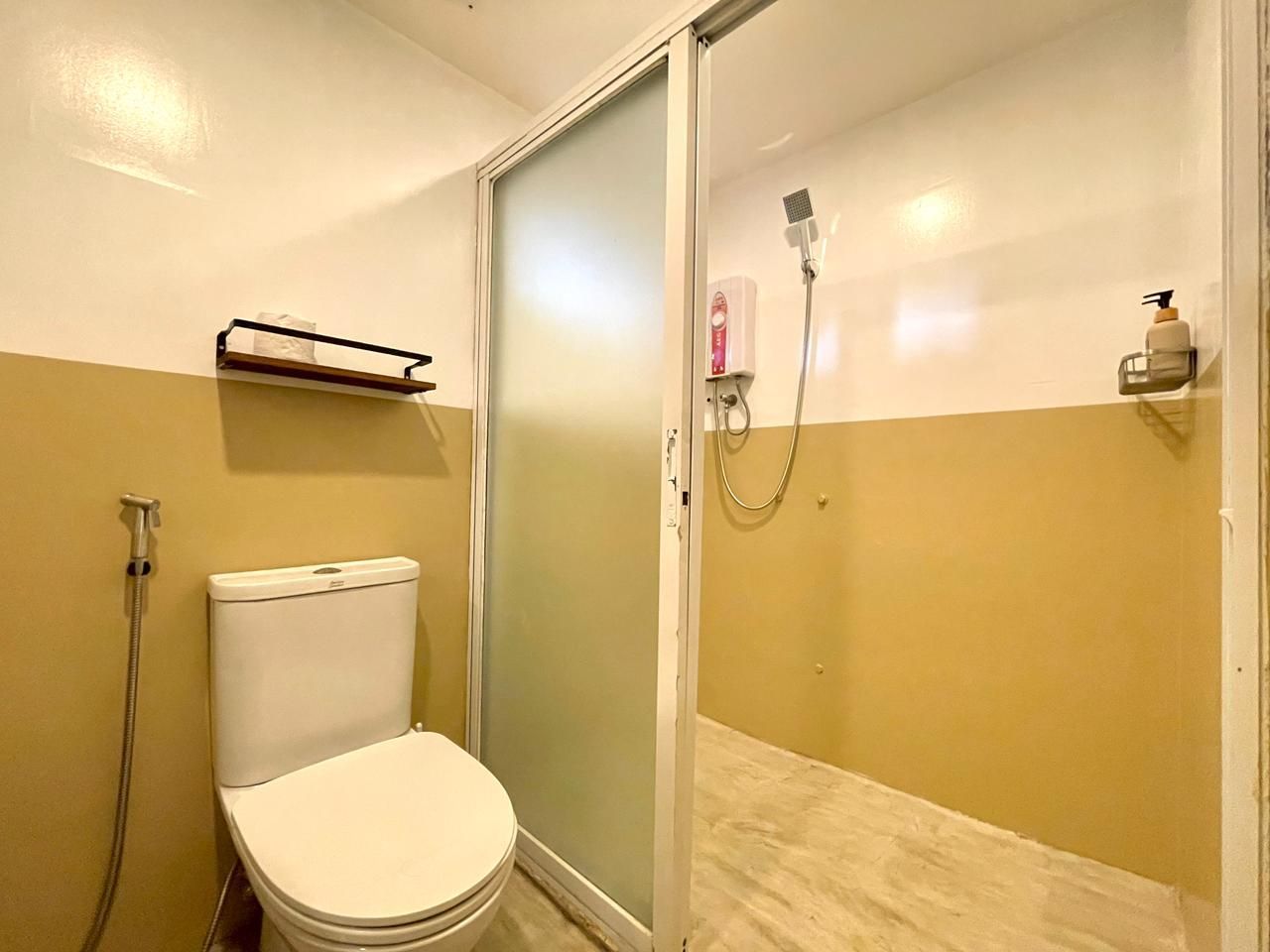 Bathroom with a toilet, shower with glass door, and yellow and white walls.
