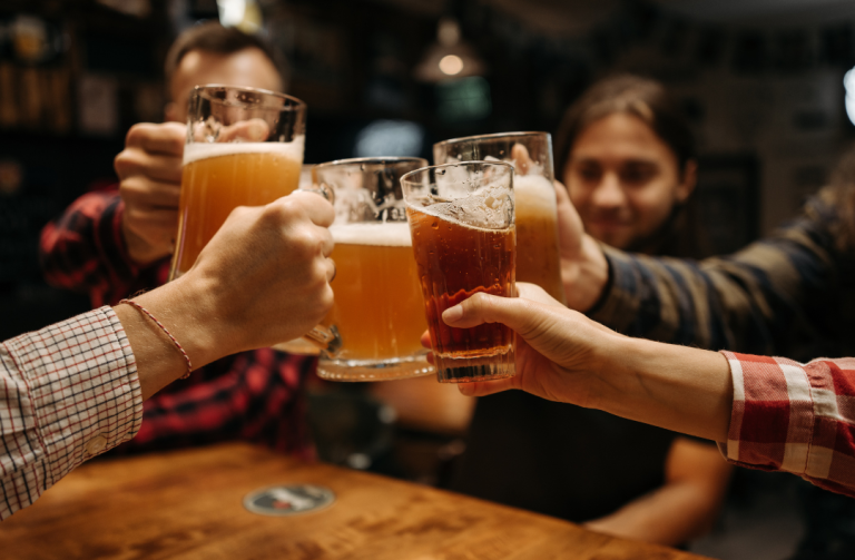 People toasting beer glasses in a bar. Various beers are held up, cheers.