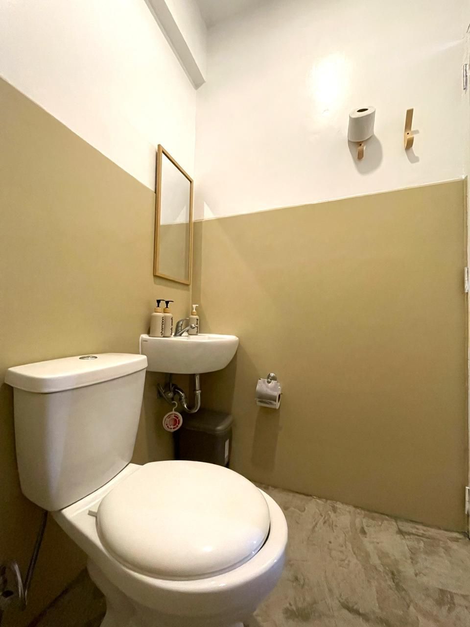 Small bathroom with white toilet, sink, and tan and white walls.