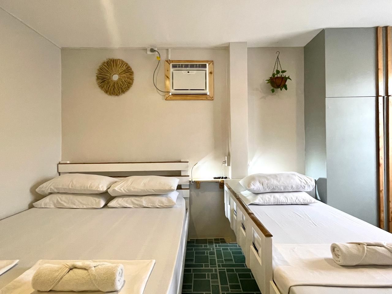Bedroom with two beds, white bedding, green tile floor, air conditioner, and wall decor.