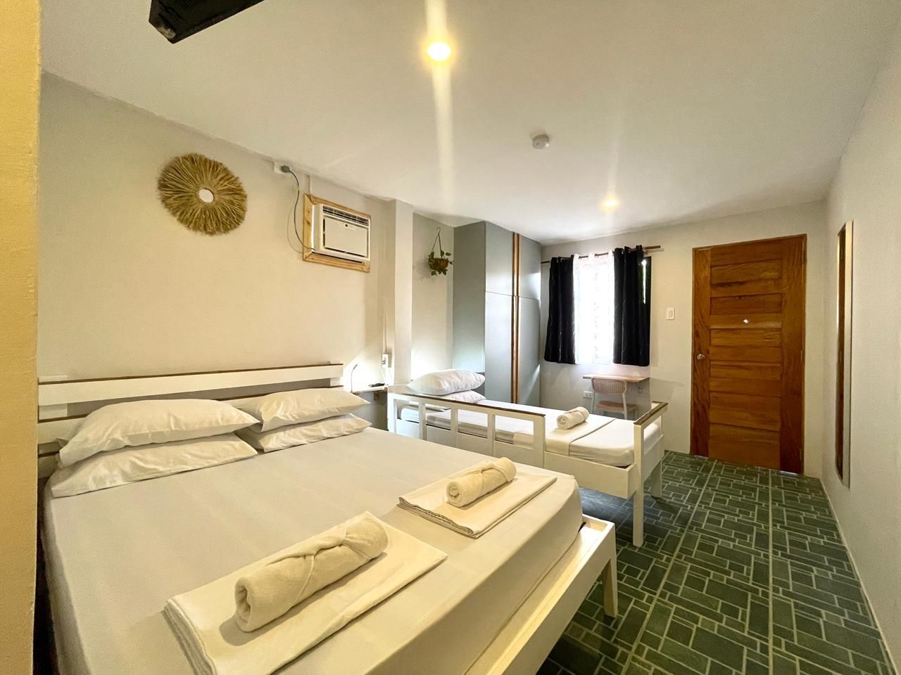 Bedroom with a queen bed, single bed, closet, and window. White linens and neutral walls.