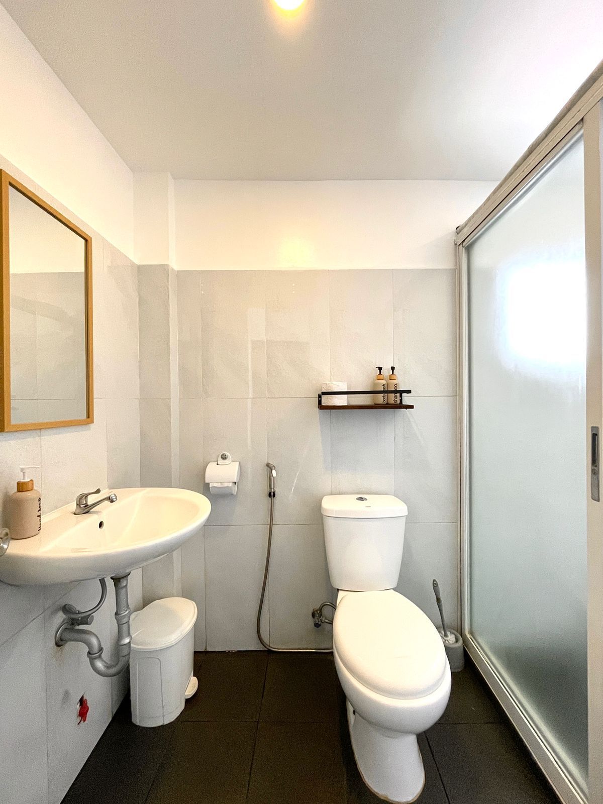 Bathroom with a toilet, sink, and glass shower door; gray and white color scheme.