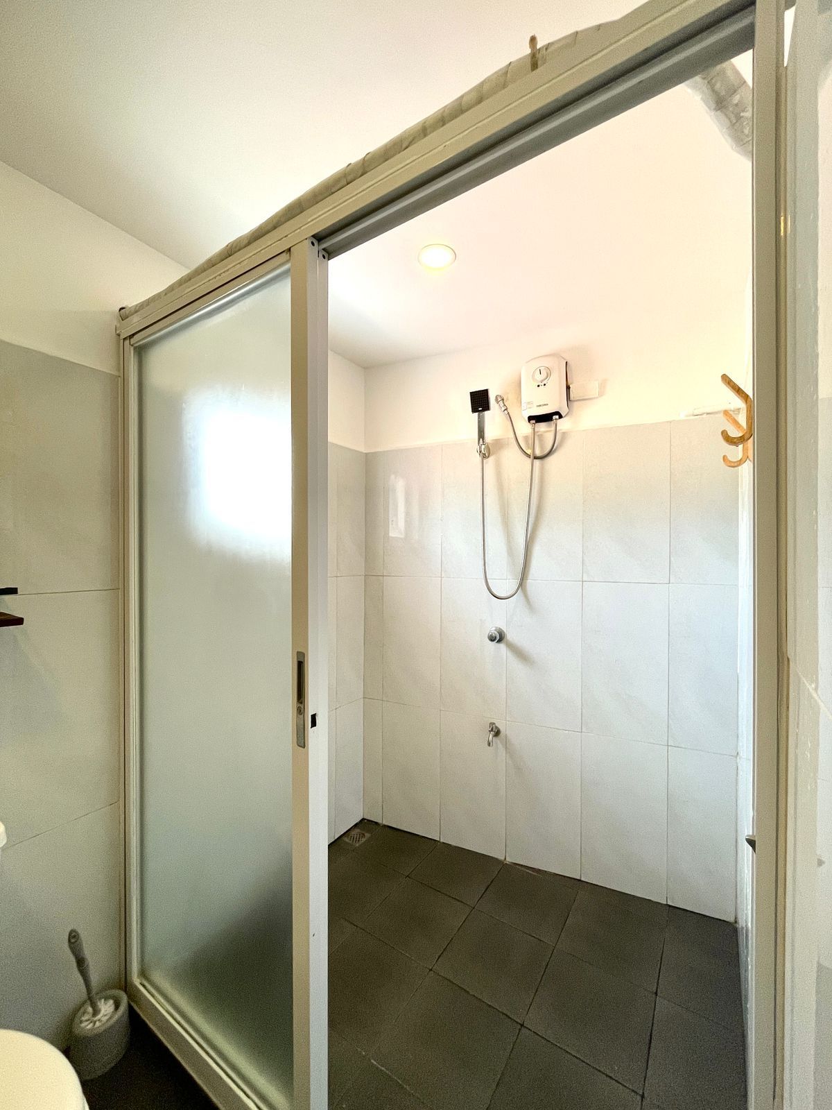 Bathroom with sliding glass shower door, white tiled walls, and a mounted water heater.