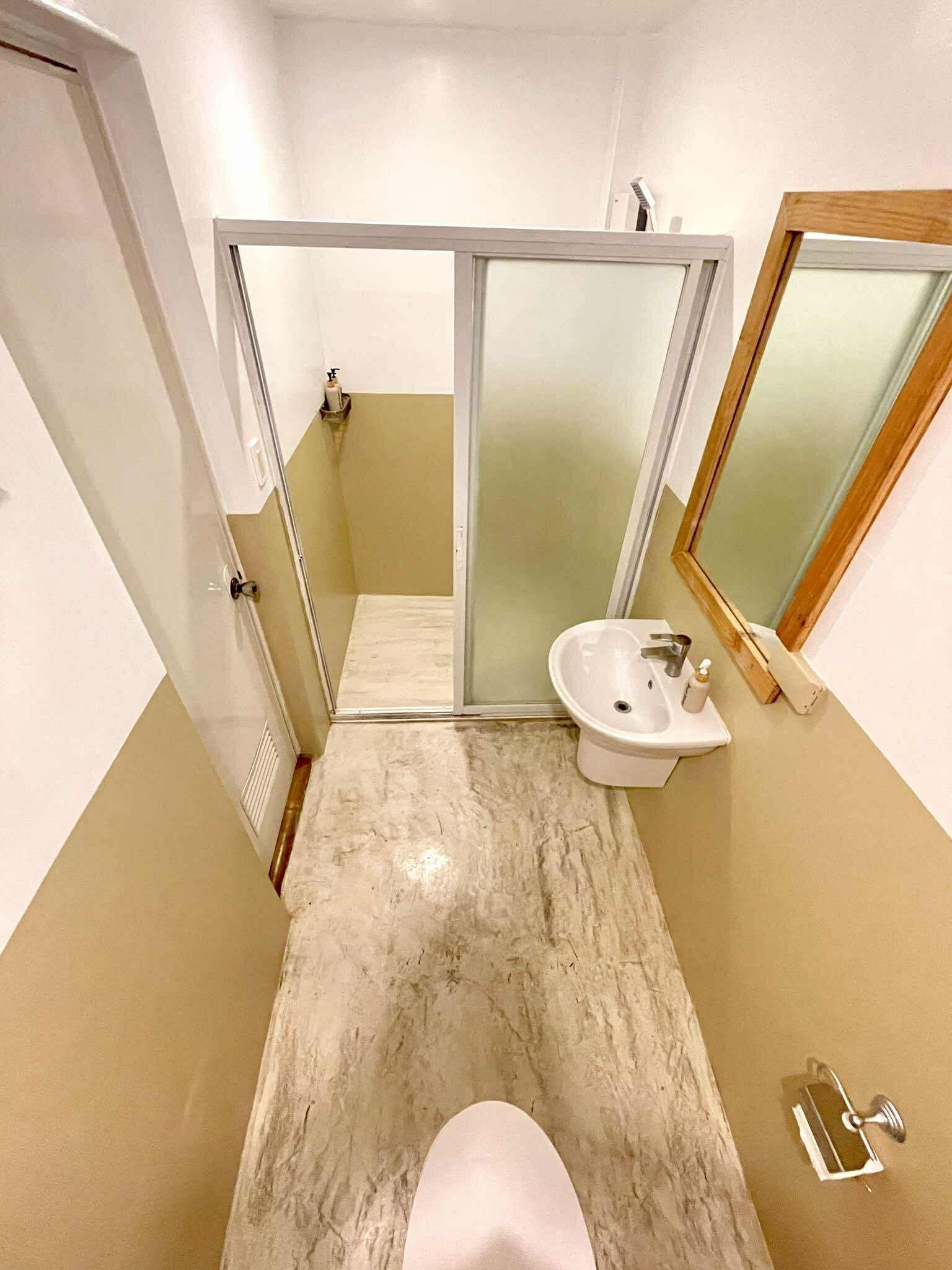 Bathroom with a shower, sink, and mirror. White and beige color scheme, overhead perspective.