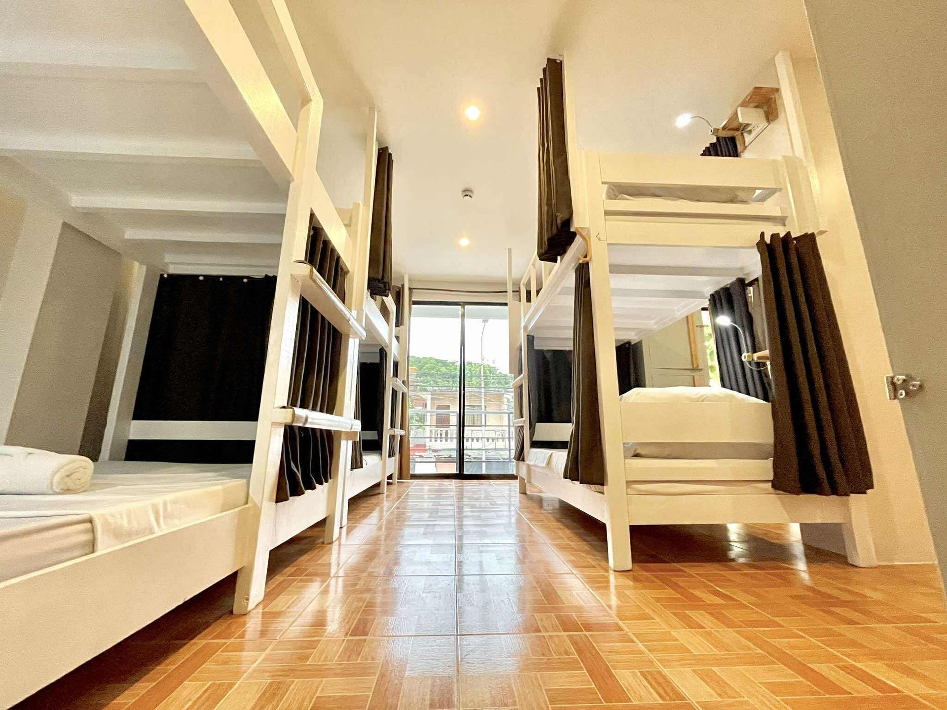 Dorm room with white bunk beds, brown curtains, and wooden floor.