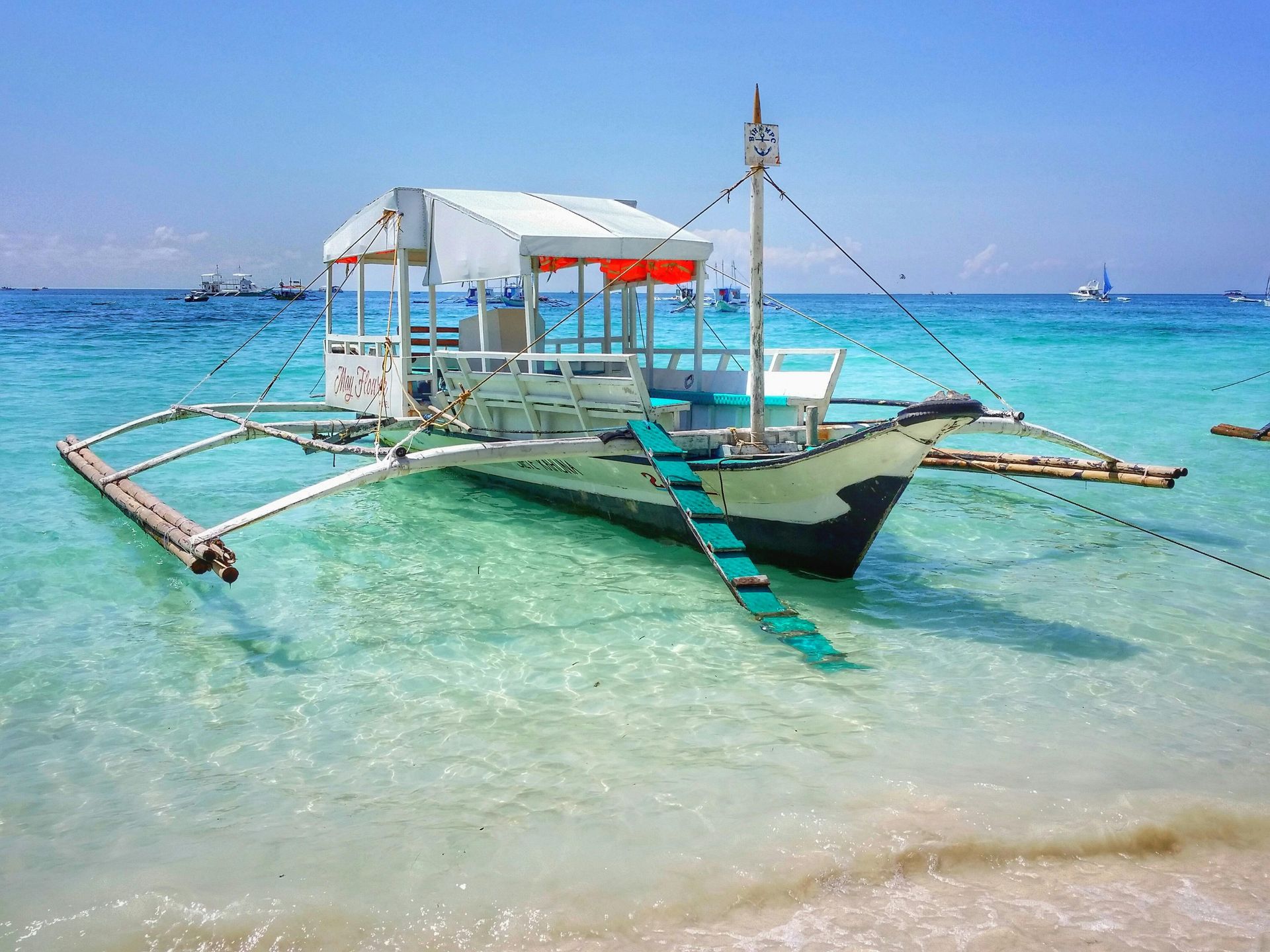 Boat with a white roof on turquoise water near shore.