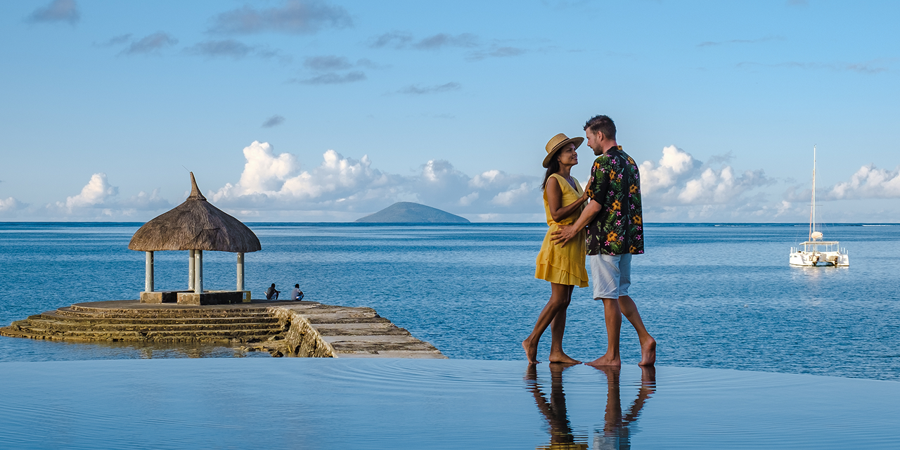 A man and a woman are standing next to each other on a dock overlooking the ocean.