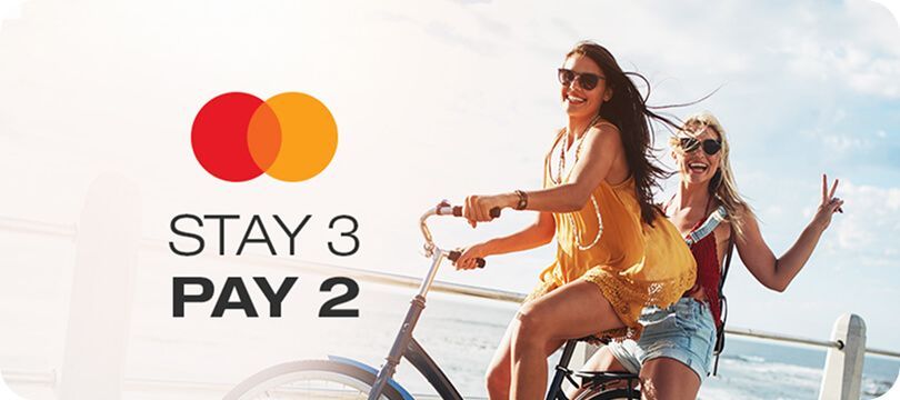 A group of women are riding a bike on a beach.