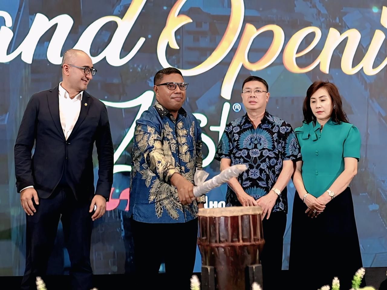 Four people at signing ceremony, two shaking hands. Backdrop reads 