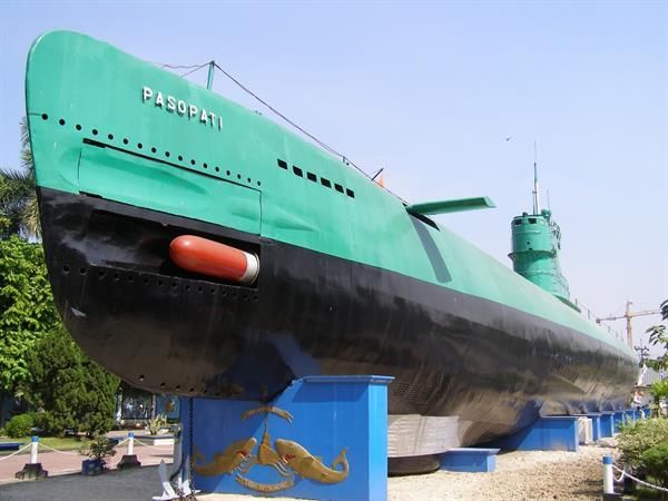 A green and black submarine is on display in a park