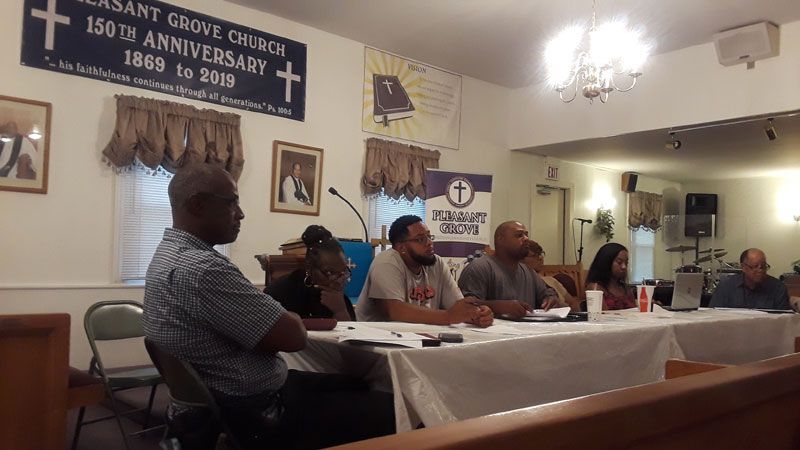 A group of people are sitting at a table in front of a sign that says 150th anniversary