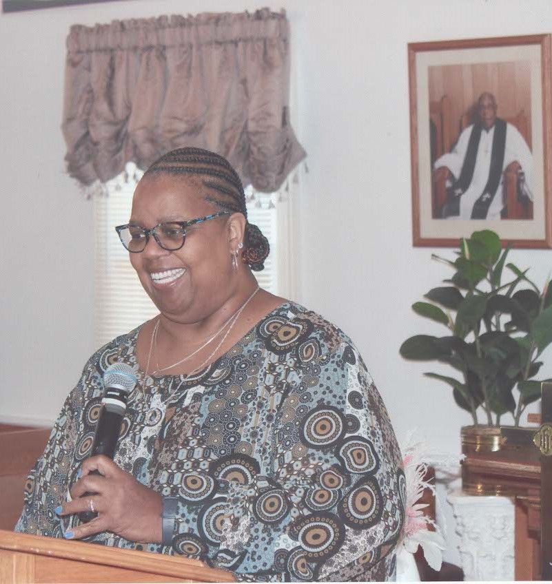 Two women wearing white gloves are dancing in front of a microphone