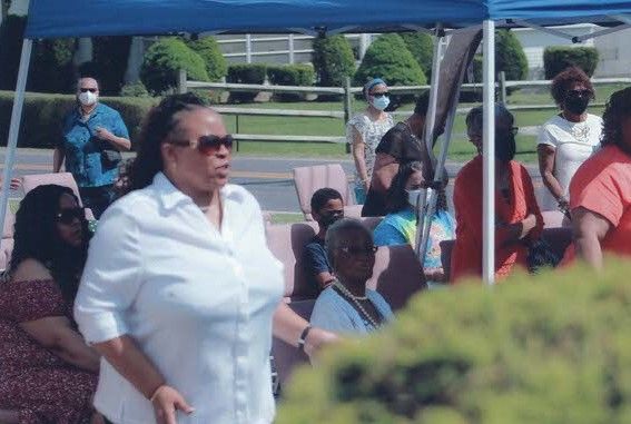 A woman in an orange dress is holding a microphone and smiling.