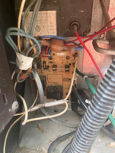 The inside of a refrigerator with a lot of wires coming out of it.