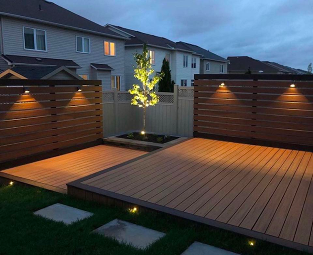 A backyard with a wooden deck and a fence