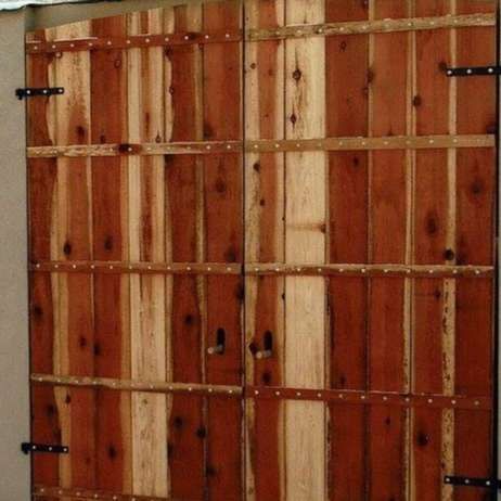 Wooden double doors with horizontal wood panels and metal hinges.