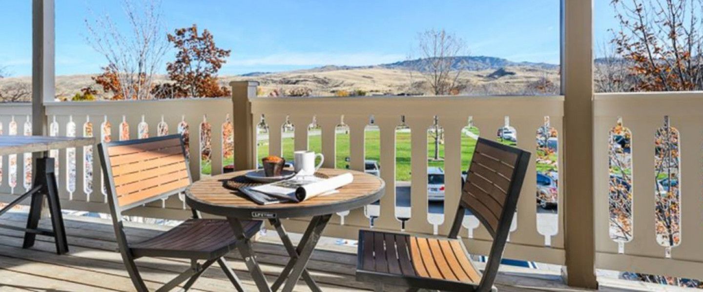 A wooden table with coffee and newspaper, two chairs, and a view of a mountain range.