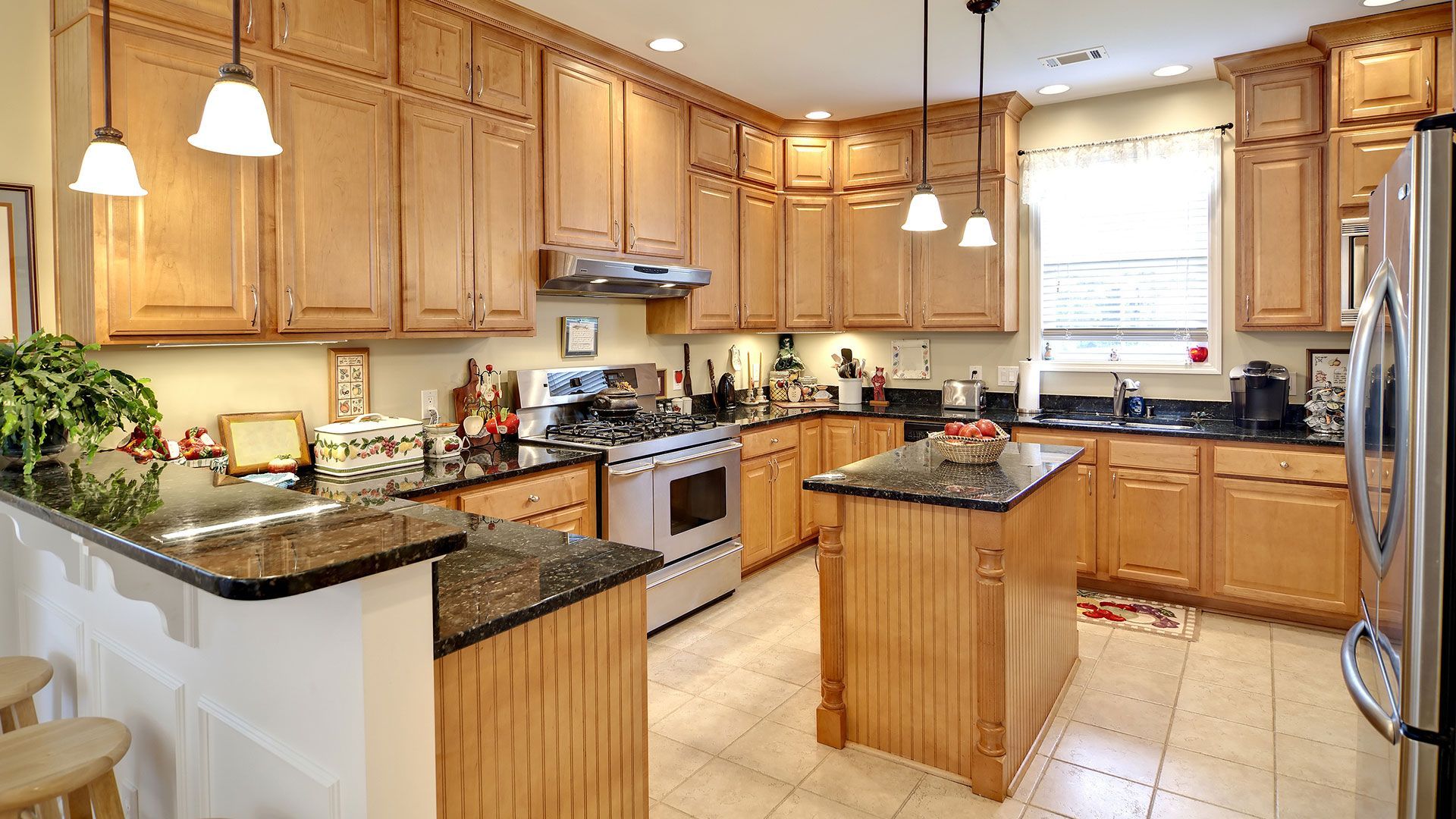 Kitchen with light wood cabinets, granite countertops, and stainless steel appliances.