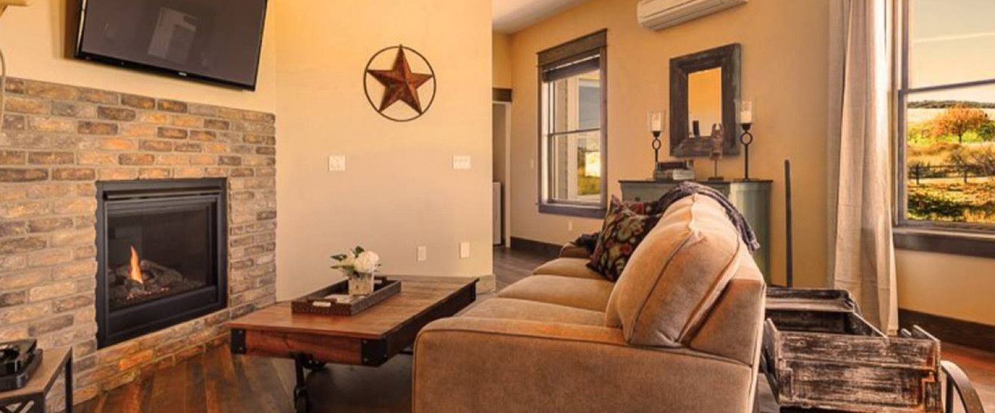 Living room with fireplace, sofa, wooden coffee table, star wall decor, window with autumn view.