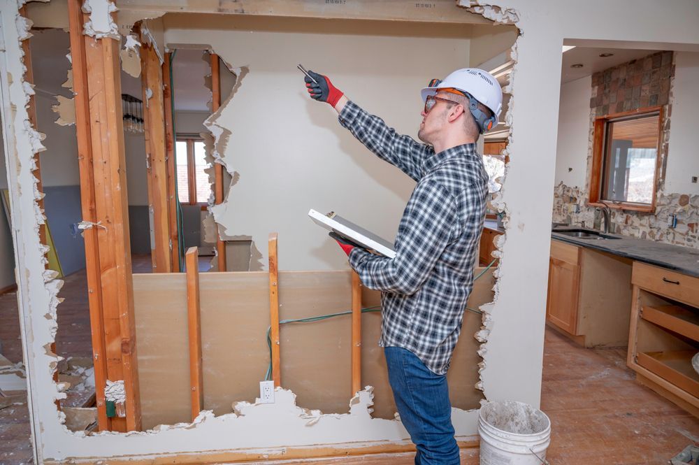 Person in hard hat examining a wall during a home renovation.
