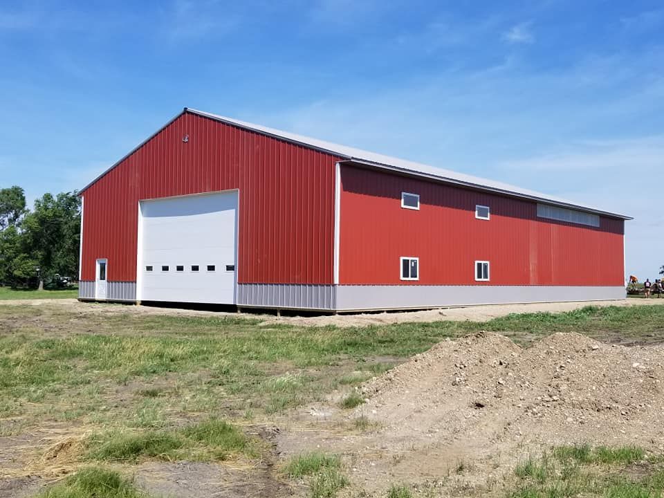 A large red barn is sitting in the middle of a grassy field.