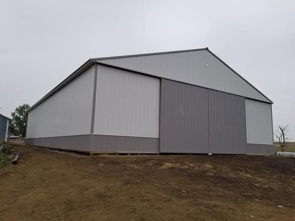 A large building with a sliding door is sitting on top of a dirt field.