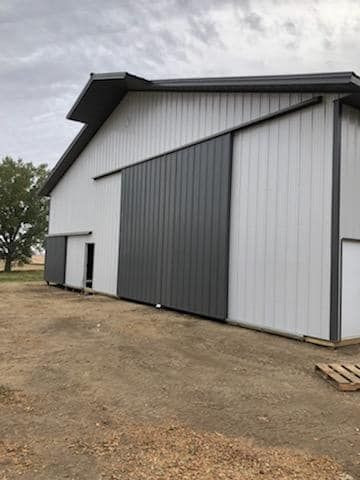A white barn with a gray sliding barn door.