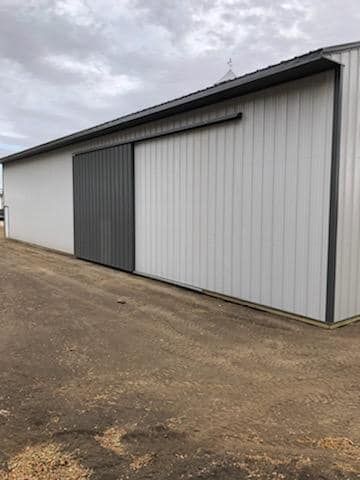 A large white barn with a sliding door on the side of it.