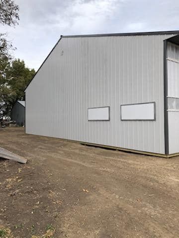 A large white building with a lot of windows is sitting on top of a dirt field.