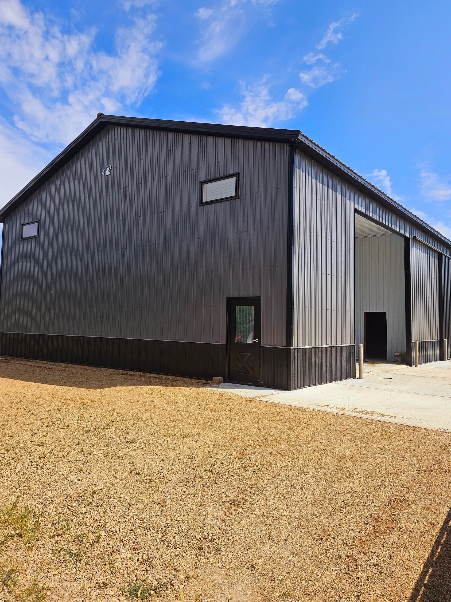 A large metal building is sitting in the middle of a field.