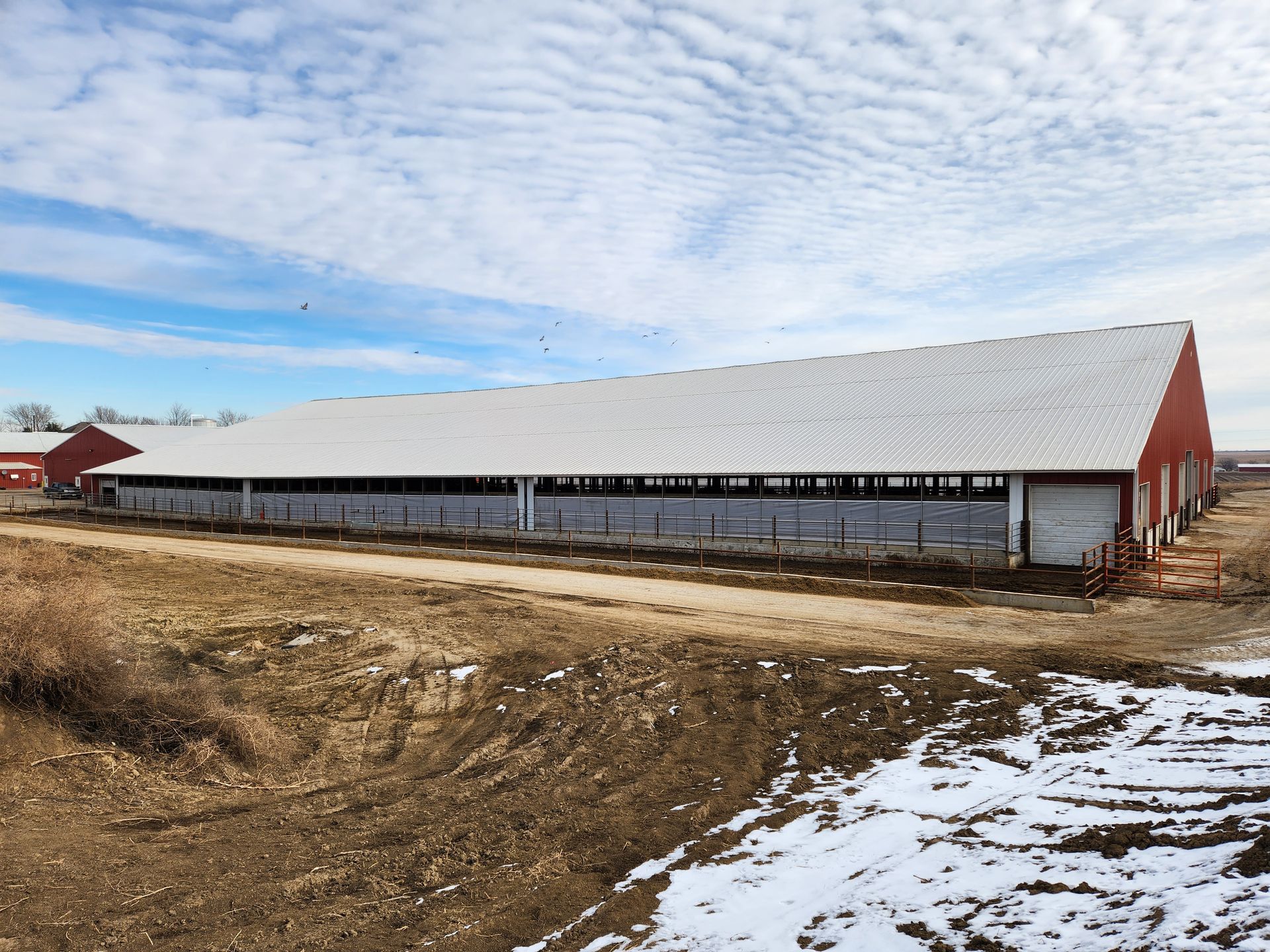 A large barn is sitting in the middle of a dirt field.