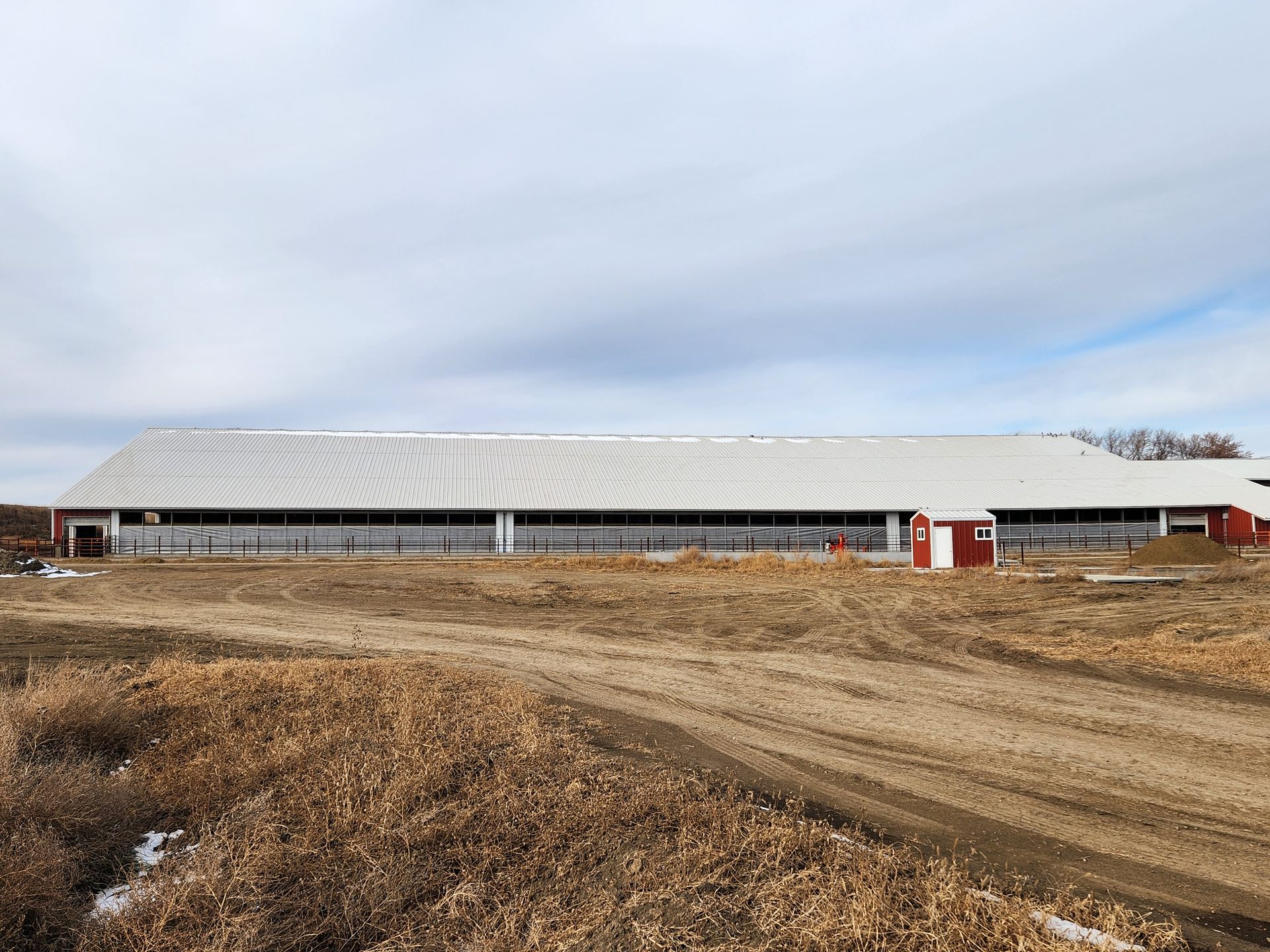 A large barn is sitting in the middle of a dirt field.