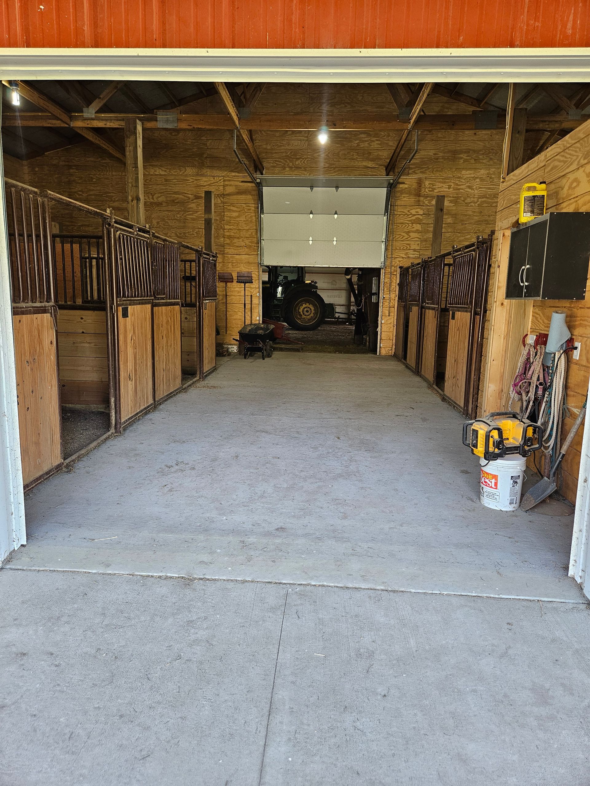The inside of a horse barn with a garage door open.