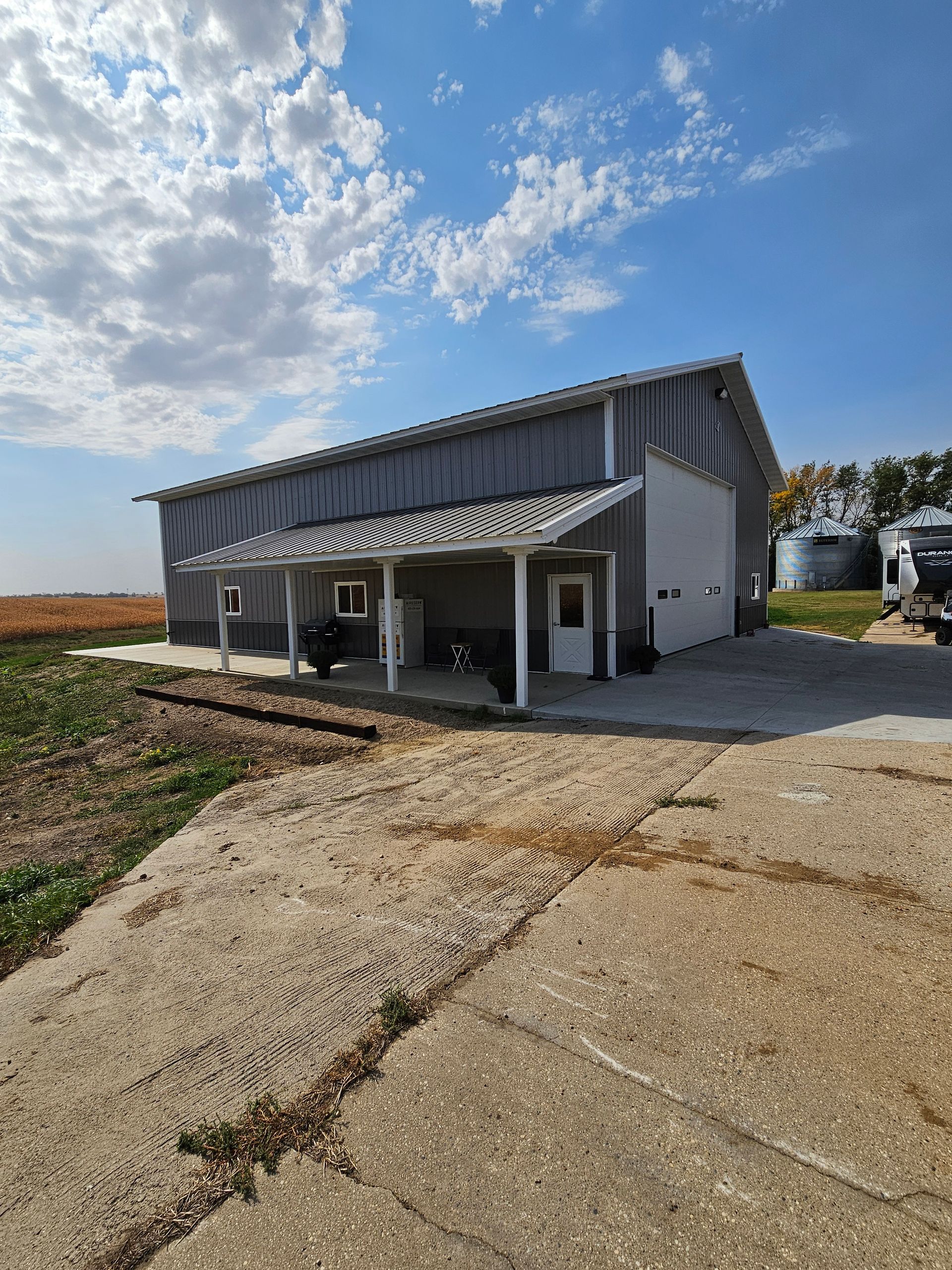 A large barn with a porch and a car parked in front of it.