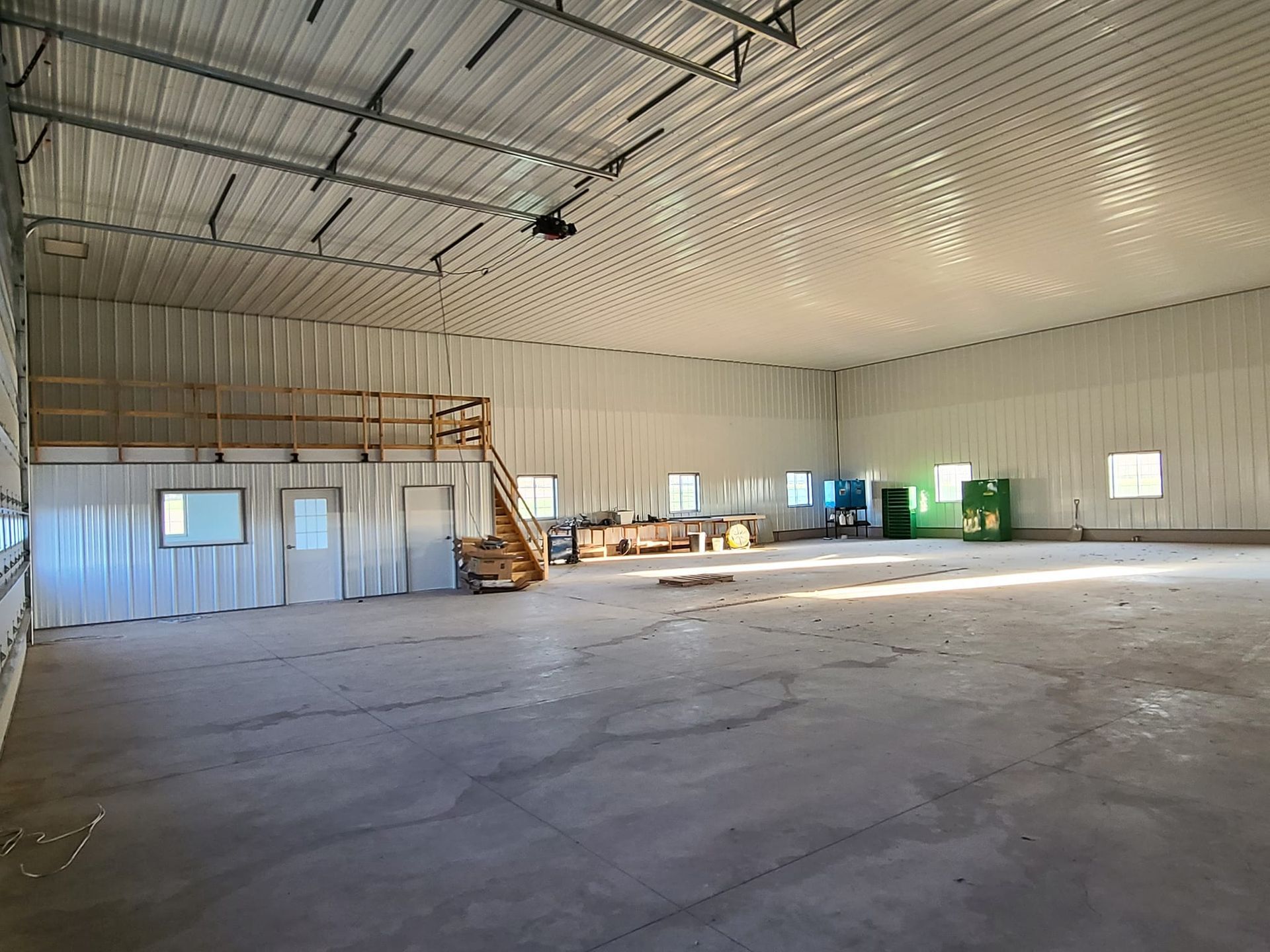 A large empty warehouse with a staircase leading up to the second floor.